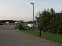 De asfaltvlakte, rechts achter bomen meer