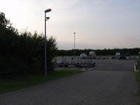 De asfaltvlakte, links achter bomen meer